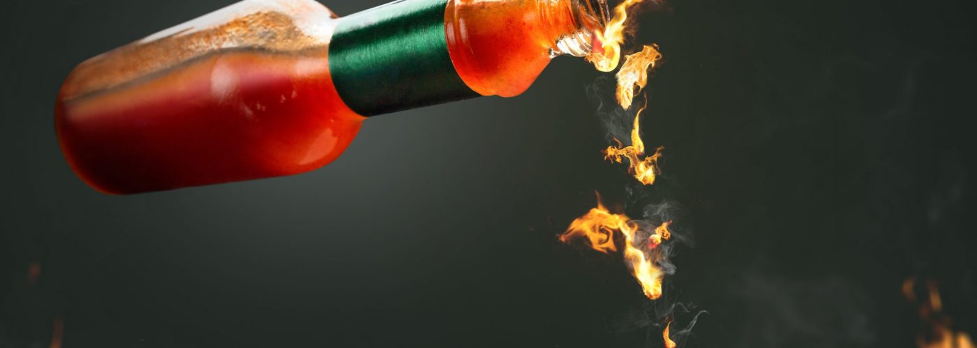 Burning hot chili sauce dripping from a bottle